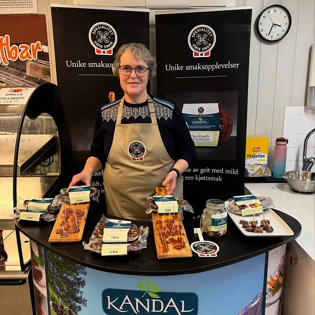 Kvinne bak Kandal-stand med spekemat og smaksprøver på disken.