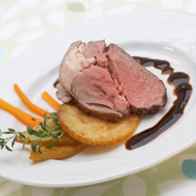 Tallerken med grilla kjøt, lauk og urter på flatbrød med saus og grønsaker.