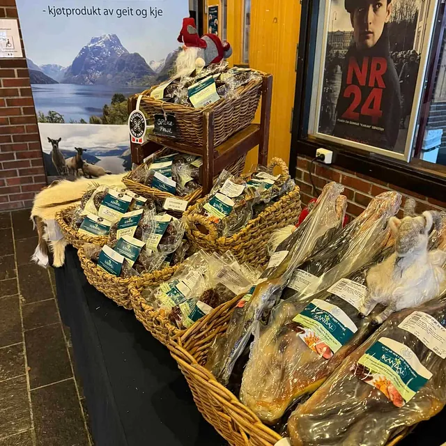 Salsbord med spekemat i korgar og Kandal-plakat på messestand innandørs.